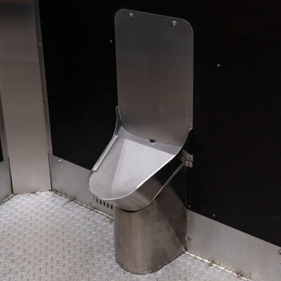 Edelstahl-Unisexurinal in der Libre Trockentoilette vor schwarzer Wand.