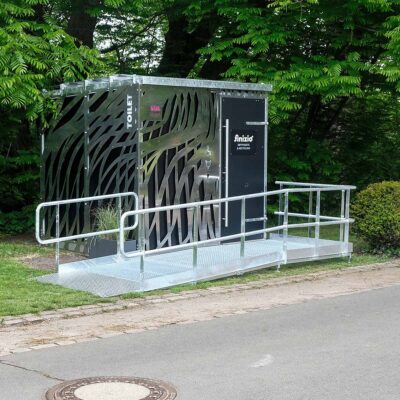 Außenansicht der Libre-DIN-Kabine mit Edelstahlverkleidung und rollstuhlgerechter Rampe aus verzinktem Stahl im Ammonpark Eberswalde.