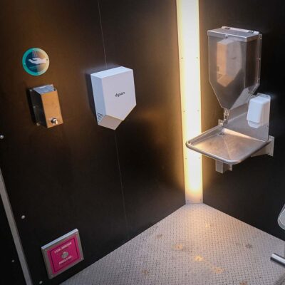 Innenansicht der Libre-DIN Kabine mit Dyson Händetrockner, Edelstahl-Desinfektionsspender und Handwaschstation mit Seifenspender und SOS-Knopf.