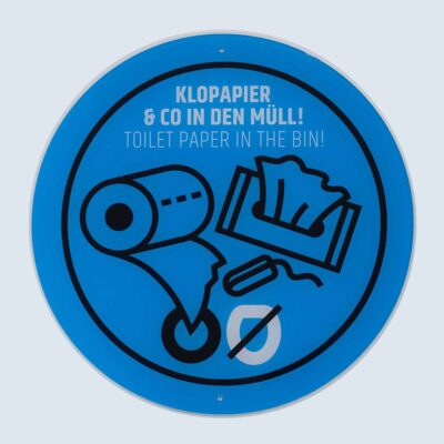 Rundes blaues Schild mit Symbolen und Text „Klopapier & Co in den Müll / Toilet paper in the bin“.