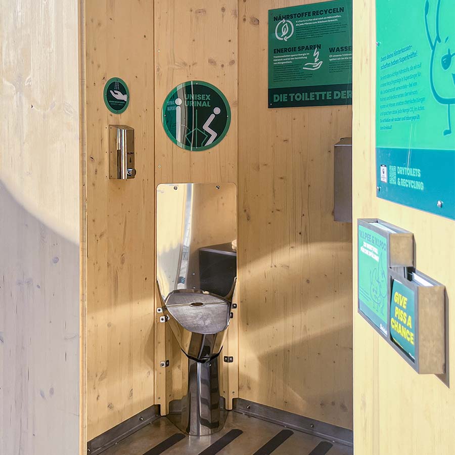 Blick die mobilde Toilette Humero auf das Unisexurinal und Schild.