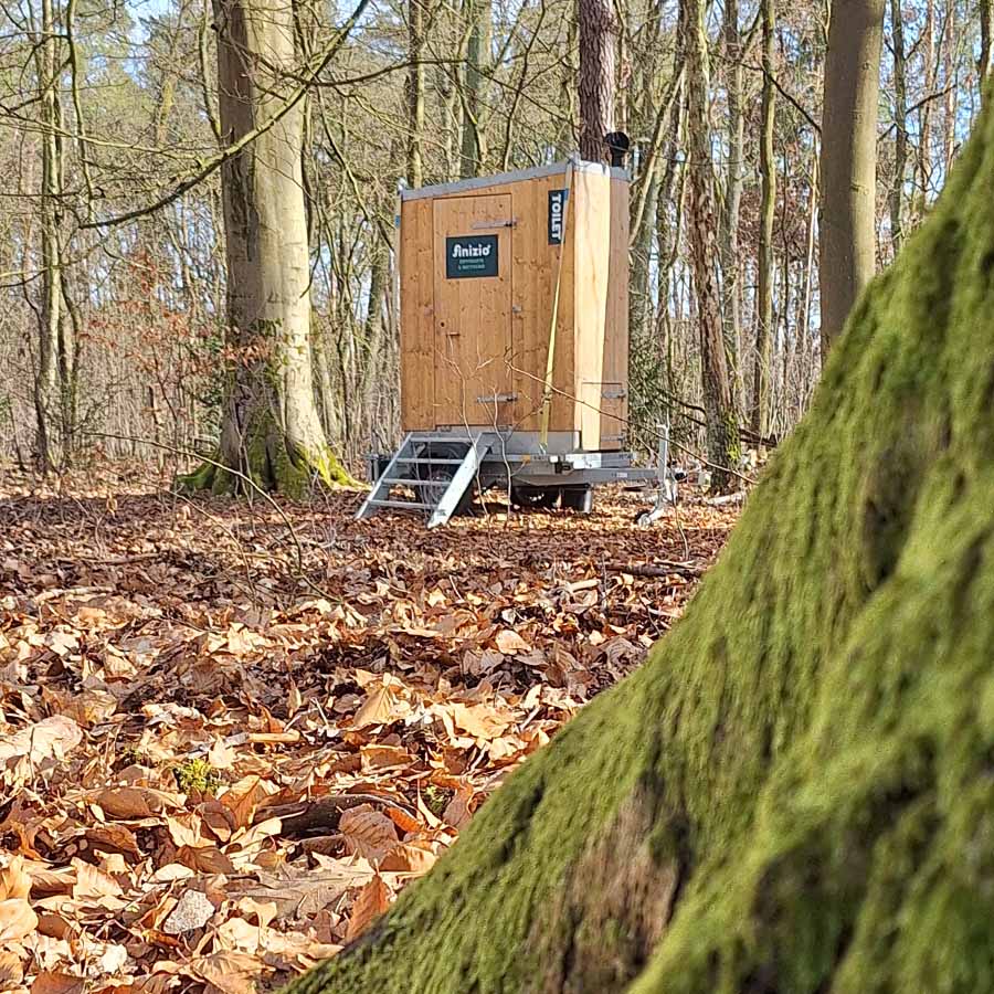 Eine Toilette aus Holz in einem herbstlichen Wald